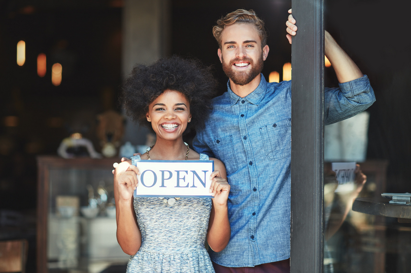 Man and woman holding "OPEN" sign
